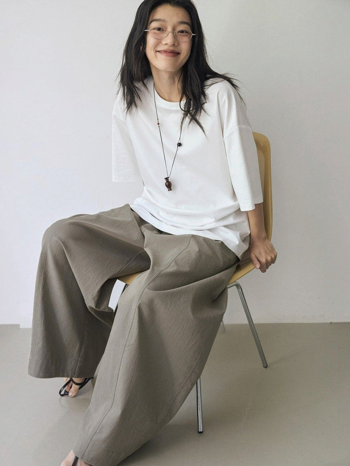 IROHI 模特身穿宽松的棕色立体曲线长裤，搭配白色T恤，展现休闲舒适的穿搭风格。