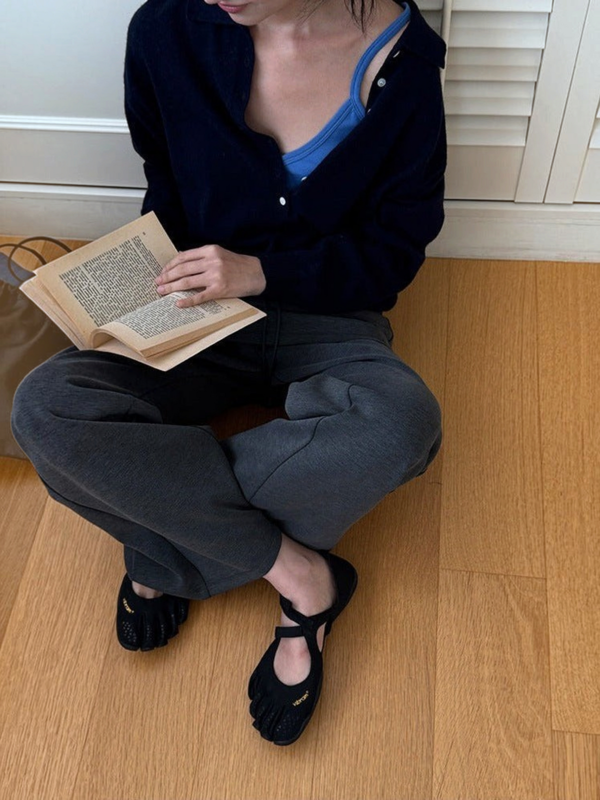 IROHI 穿着深蓝色羊毛混纺亨利领长袖针织衫的女性，内搭亮蓝色吊带，展现舒适休闲的秋季穿搭风格。