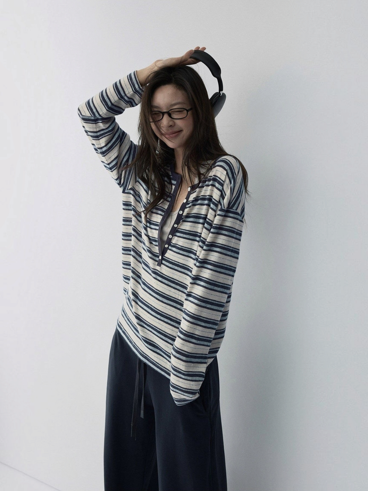 IROHI的蓝白条纹亨利领长袖T恤，采用天丝混纺面料，模特佩戴耳机和眼镜，展现休闲舒适的秋冬穿搭风格。